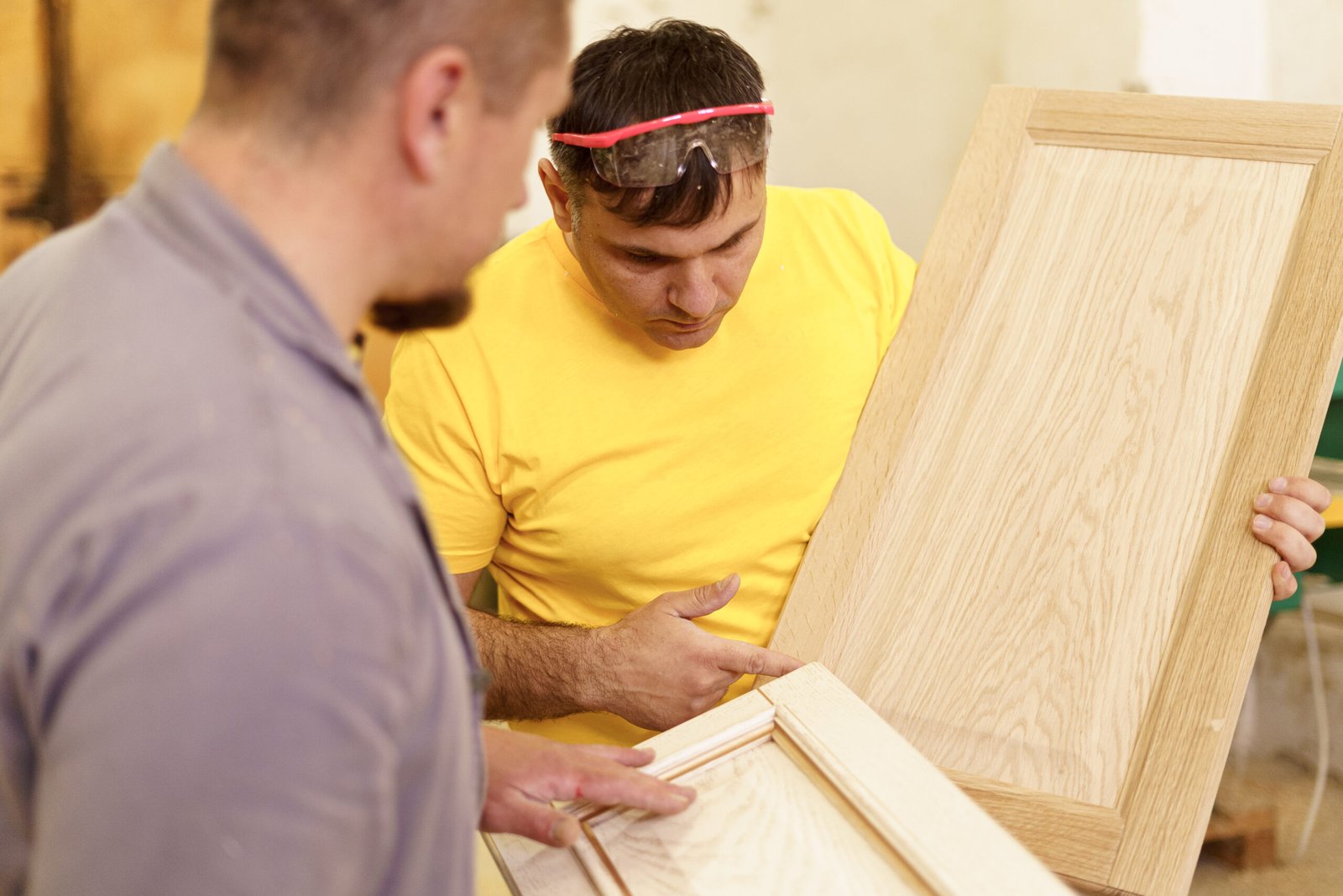 Profession, carpentry, woodwork and people concept - two carpenterswork with wood for furniture at workshop.
